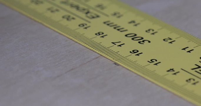 Drawing a straight line with ruler and pencil on a wooden surface