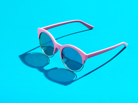 Pink sunglasses on pastel blue background