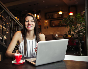 Young pretty caucasian woman in cafe in city centre with tablet laptop