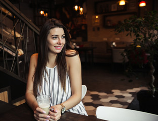 Young pretty woman blogger in cafe with smartphone