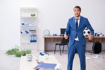 Young male employee playing football in the office