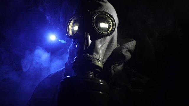 Environmental disaster. Post-apocalyptic survivor in gas mask on a dark background. Dramatic portrait of a man wearing a gas mask. Means for radiation protection. Selective focus