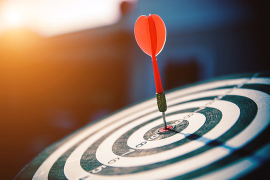 Bullseye(bull's-eye) or dart board has dart arrow hitting the center of a shooting target for business targeting and good success.