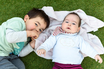 Hermanos felices tumbados sobre cesped verde
