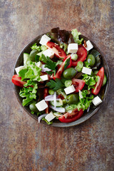  Healthy salad with feta cheese, green olives and tomatoes. Rustic stone background. Top view.