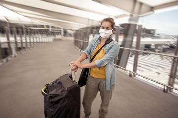 Traveler with face mask affected by coronavirus travel ban and COVID-19 pandemic flight restrictions