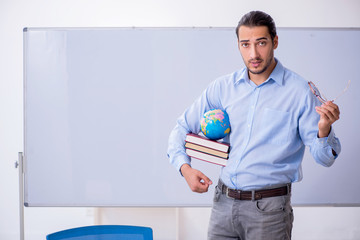Young male geography teacher in front of whiteboard