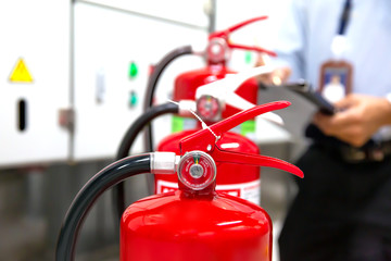 Engineer are checking and inspection a red fire extinguishers in the fire control room for safety...