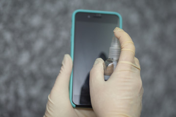 Hand of woman is spraying alcohol,disinfectant spray on mobile phone,prevent infection of Covid-19 virus,contamination of germs or bacteria,wipe or cleaning phone to eliminate,outbreak of Coronavirus