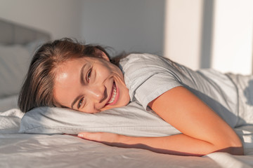 Happy home relaxation asian smiling woman staying in bed relaxing in bedroom candid portrait....