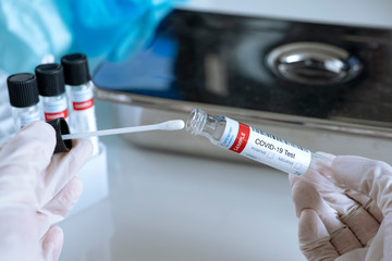 Testing for presence of coronavirus. Tube containing a swab testing for COVID-19.
