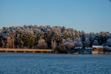 Snow covered trees on a clear sunny morning at the boathouse at Lake Johnson Park in Raleigh, North Carolina.