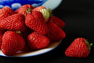 Strawberry in white plate isolated on black background
