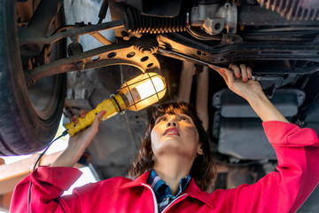 Woman Mechanic Examining Under the Car at the Repair Garage.