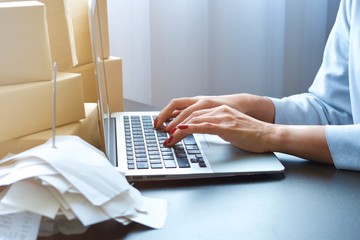 Asian woman is typing on keyboard of laptop or computer notebook for check electronic mail, preparation for delivery product order, get information for shopping online or operation of internet banking
