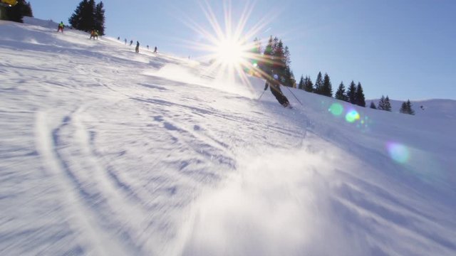 male skier skiing on slopes in the Swiss alps,sun rays and flare visible