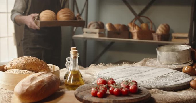 Positive elderly professional caucasian baker bringing fresh bread loafs basket, looking at camera and smiling. Retiree enjoying his new hobby portrait shot 4k footage