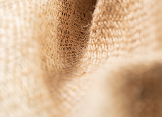 Fototapeta premium Close up view on crumpled sackcloth. Brown burlap fabric, abstract background. Texture of brown baline. Selective soft focus. Blurred background