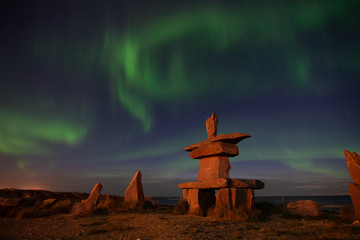 northern lights in churchill manitoba with an iconic inukshuk in the foreground