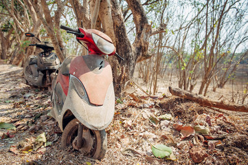 Rusty, abandoned motor scooters in country. Two old damaged scooters covered in dust, close up. Non-touristic place in India.