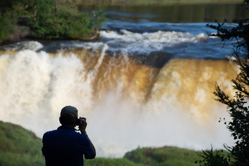 photographer taking a picture of a big waterfall in manitoba