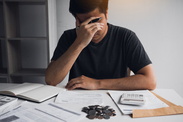 Asian men are stressed about financial problems, with invoices and calculators placed on the table...