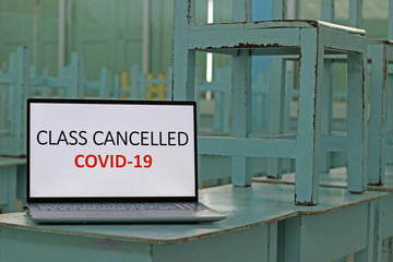 Sign on a computer laptop on desk in an empty school classroom reads ‘Class Cancelled’ because of Covid-19 coronavirus outbreak