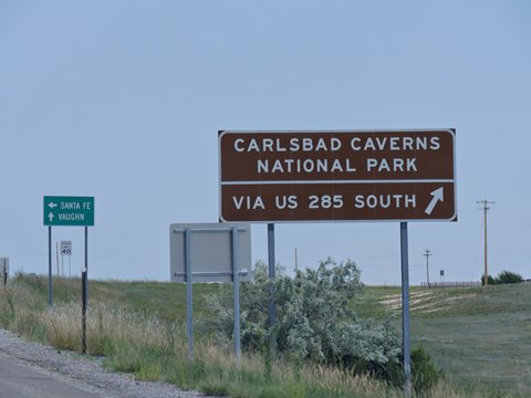 Medium close up shot of directional signs on the highway with directions to Carlsbad Caverns National Park in New Mexico.