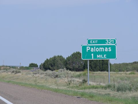 Directional sign on the highway with directions to Palomas, New Mexico.