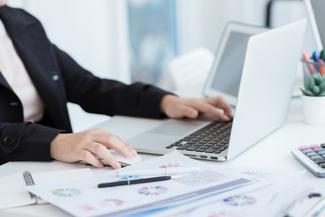 Business woman using a calculator to calculate the numbers on his desk in a office.