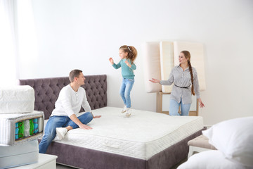 Happy family choosing mattress in furniture store