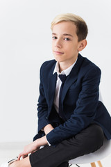 Portrait of stylish school boy teenager in white shirt and jacket against white background.