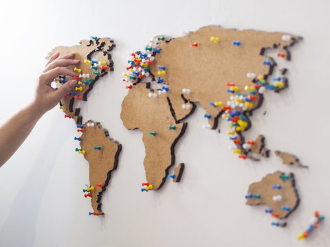 Woman Hand Putting Red Pin And Marking Location At Wooden World Map