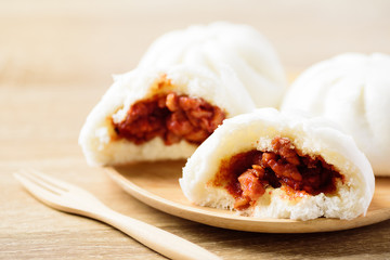 Steamed buns stuffed with red minced pork on wooden plate, Asian food
