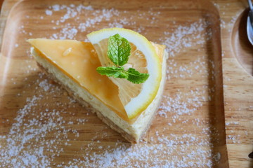 Mint leaf with  lemon fruit slice on Cheesecake pie on a wooden plate, Sweet food with brown table in background	