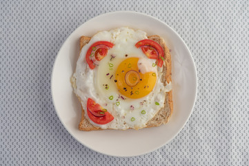 Bread placed with a fried egg with tomatoes, tapioca flour and sliced ​​spring onions.