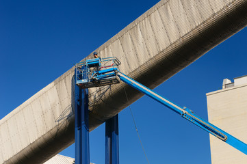 Worker moving a crane into position beside a conveyor chute for cleaning