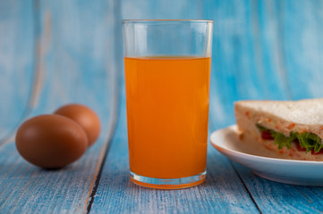 Sandwiches and orange juice on the blue wooden floor.