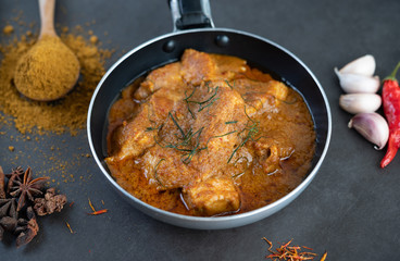 Massaman curry in a frying pan with spices on the cement floor