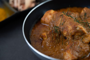 Massaman curry in a frying pan with spices on the cement floor