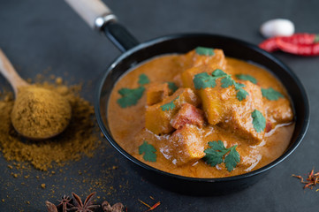 Massaman curry in a frying pan with spices on the cement floor