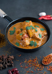 Massaman curry in a frying pan with spices on the cement floor
