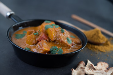 Massaman curry in a frying pan with spices on the cement floor