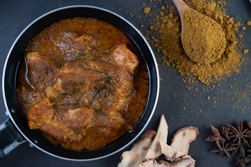 Massaman curry in a frying pan with spices on the cement floor