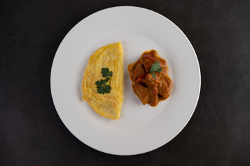 Omelette and Massaman placed on a plate on a white background.