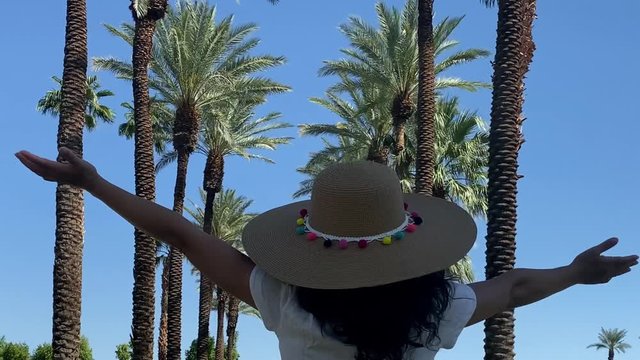 Asian woman walking down a palm tree lined path