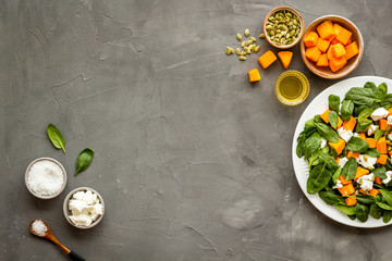 Cooking salad with pumpkin and basil. Ingredients on grey background top-down copy space