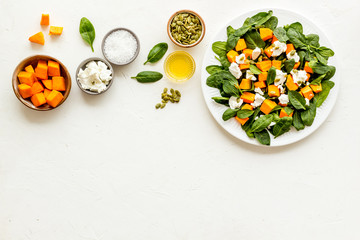 Cooking salad with pumpkin and basil. Ingredients on white background top-down copy space