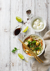 Wheat noodles, balls of mozarella and vegetables in a white plate