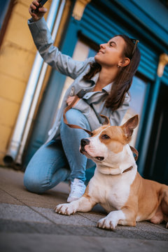  A beautiful young girl on the street taking photos of herself and her dog